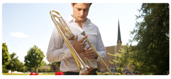 Student standing with trombone in front of the WWU church